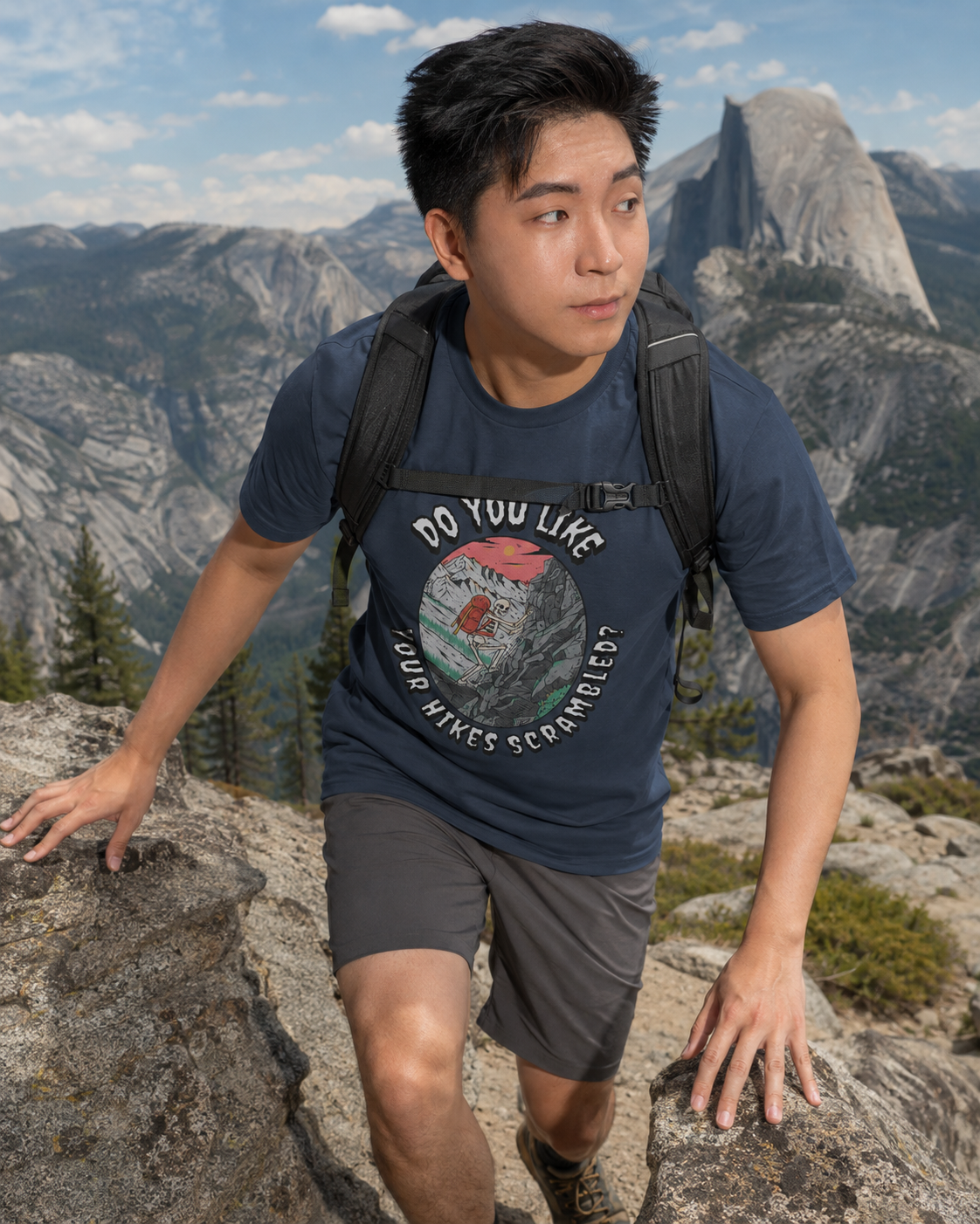 Man wearing a Heather Navy Do You Like Your Hikes Scrambled? T-shirt while scrambling up a rocky mountain trail